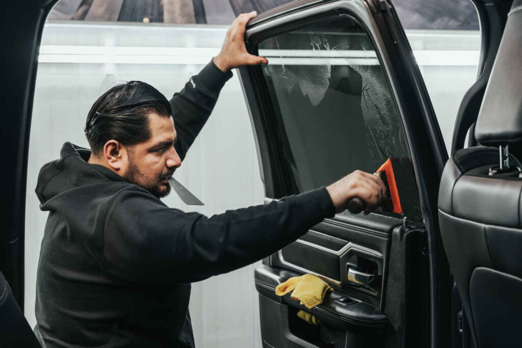 AutoPro DFW technician applying window tint to a car for UV protection and heat reduction